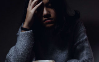 Woman looking stressed over a coffe cup