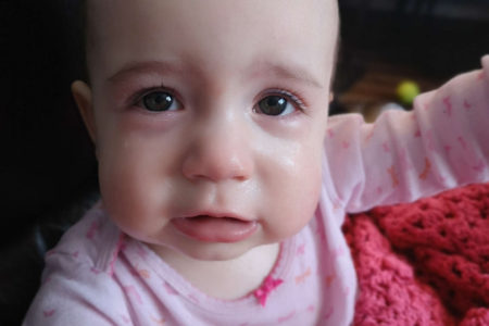 Baby crying with red nose and pale skin