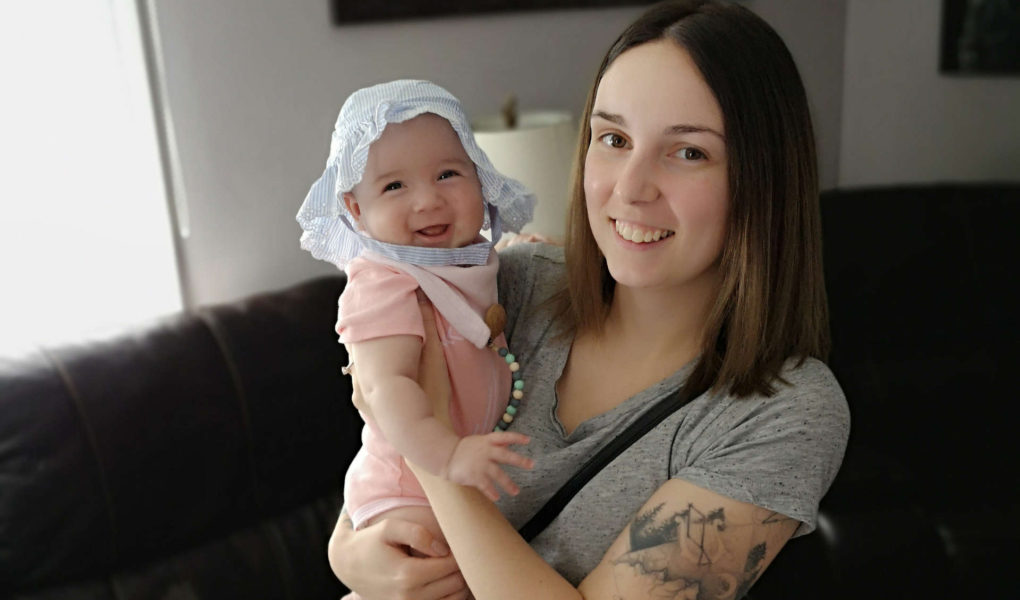 A woman is holding her baby, both are smiling.